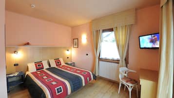 Une chambre à coucher comprenant un lit, des tables de chevet, une chaise, un téléviseur et une fenêtre avec des rideaux.