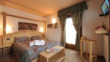 A wooden-framed bedroom with a bed, bedside table, and a small wooden stool.