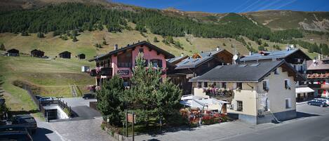 A mountain village with traditional wooden houses, a paved street, and a clear view of the surrounding hills.