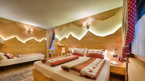 A cozy wooden cabin bedroom with two beds, a patterned rug, and a small nightstand with a lamp. - Hotel Astra (Livigno)