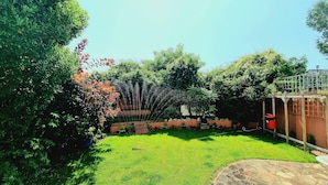A well-maintained garden with a lawn, a wooden pergola, and a brick wall. - The Ashleigh - Dog Friendly (Bournemouth)