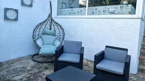 A patio area with a hanging chair, two armchairs, and a small table. - The Ashleigh - Dog Friendly (Bournemouth)