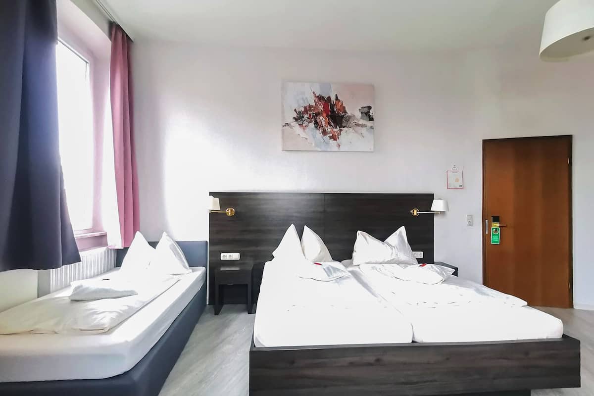 A hotel room with a bed, a sofa, a painting, and a door.