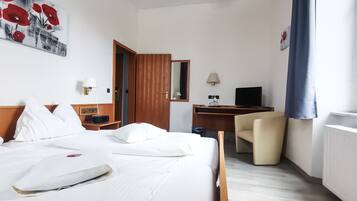 A hotel room with a bed, a desk, a chair, a TV, and a painting on the wall.