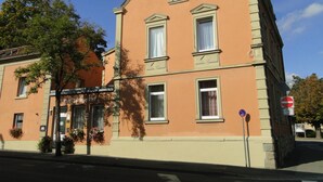 Un edificio de dos plantas con fachada simétrica, ventanas grandes y entrada en esquina.