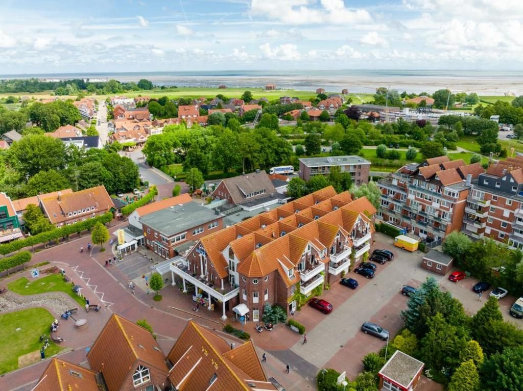A residential area with houses, a central building with a red roof, and a view of the sea.