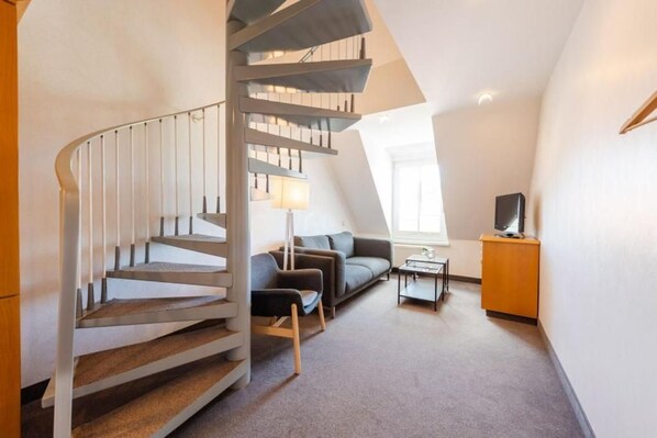 A modern interior with a spiral staircase, a sofa, a small table, and a television.