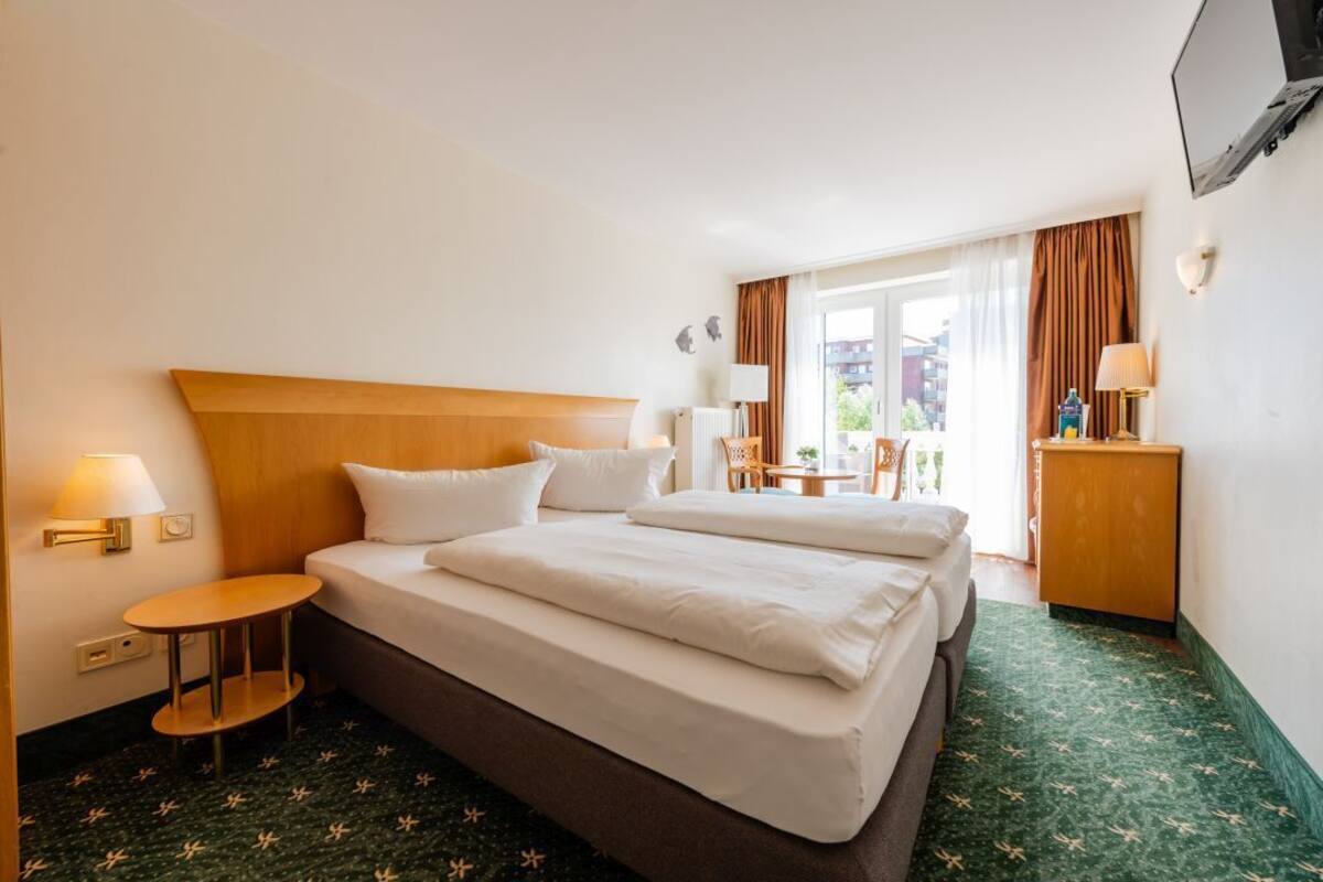 Une chambre d’hôtel avec un grand lit, une petite table, une chaise, une lampe et un téléviseur.