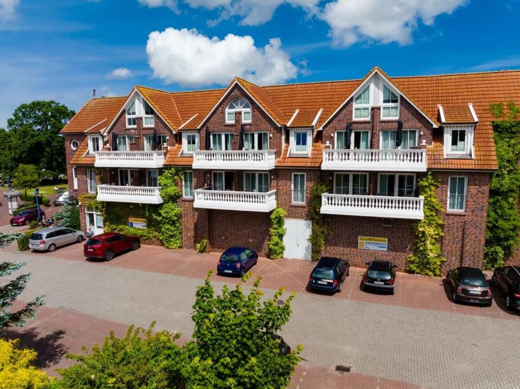 A row of brick houses with attached balconies, a paved driveway, and parked cars.