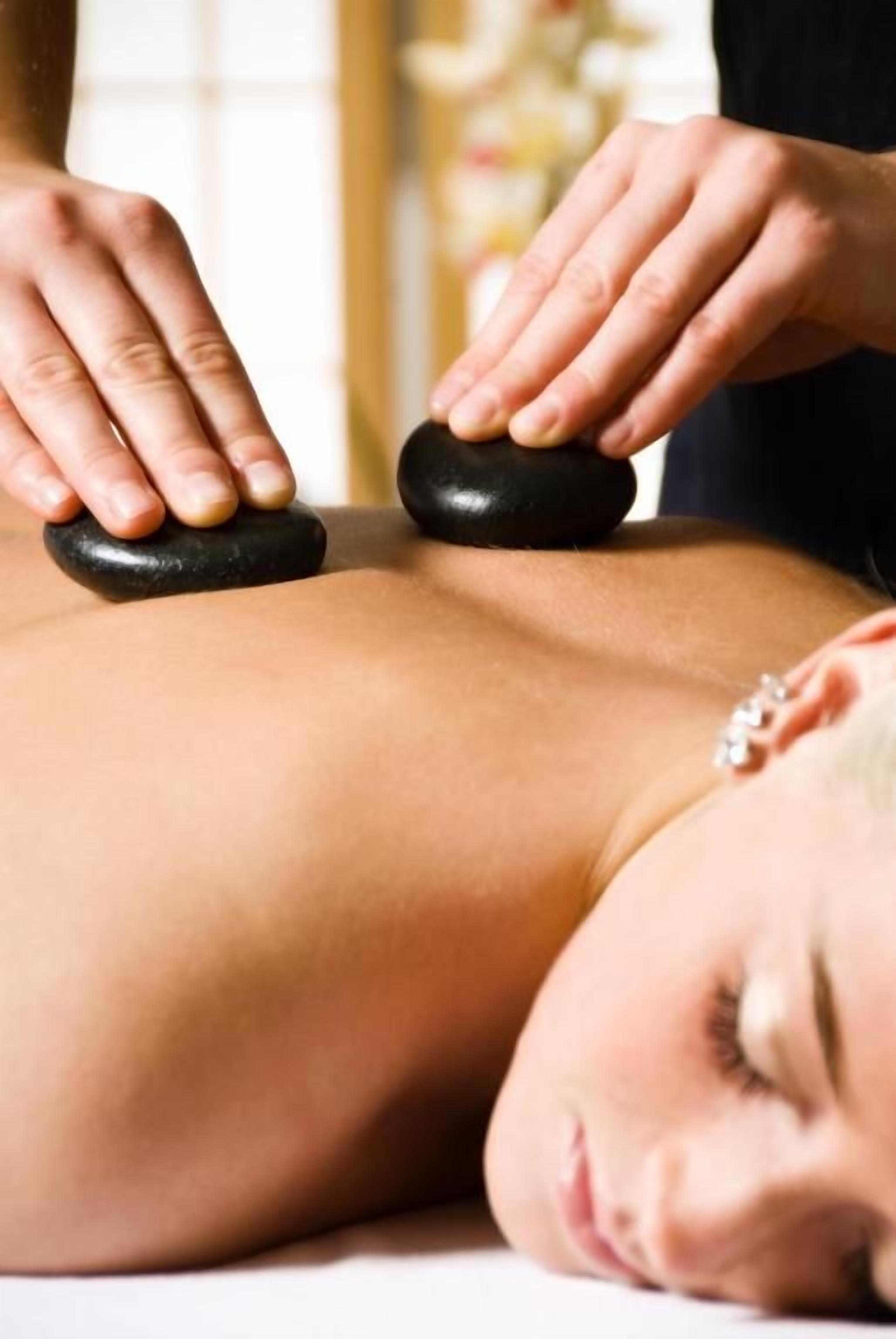 A person receiving a back massage with a stone on their back.