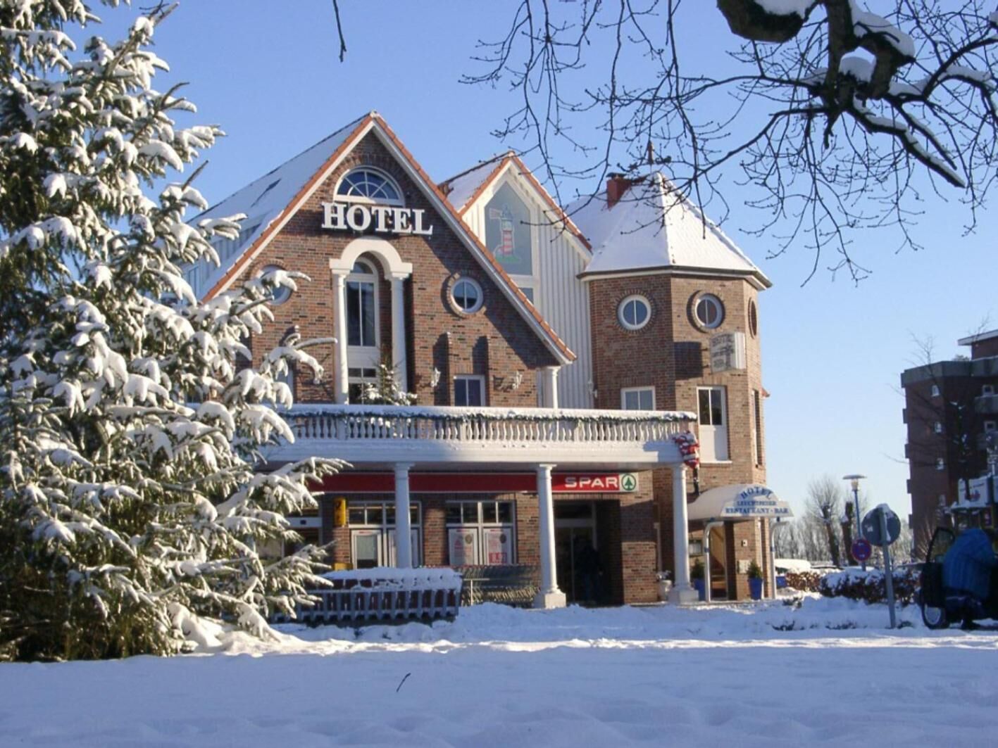 A hotel with a prominent 'HOTEL' sign, a brick facade, and a snow-covered landscape.
