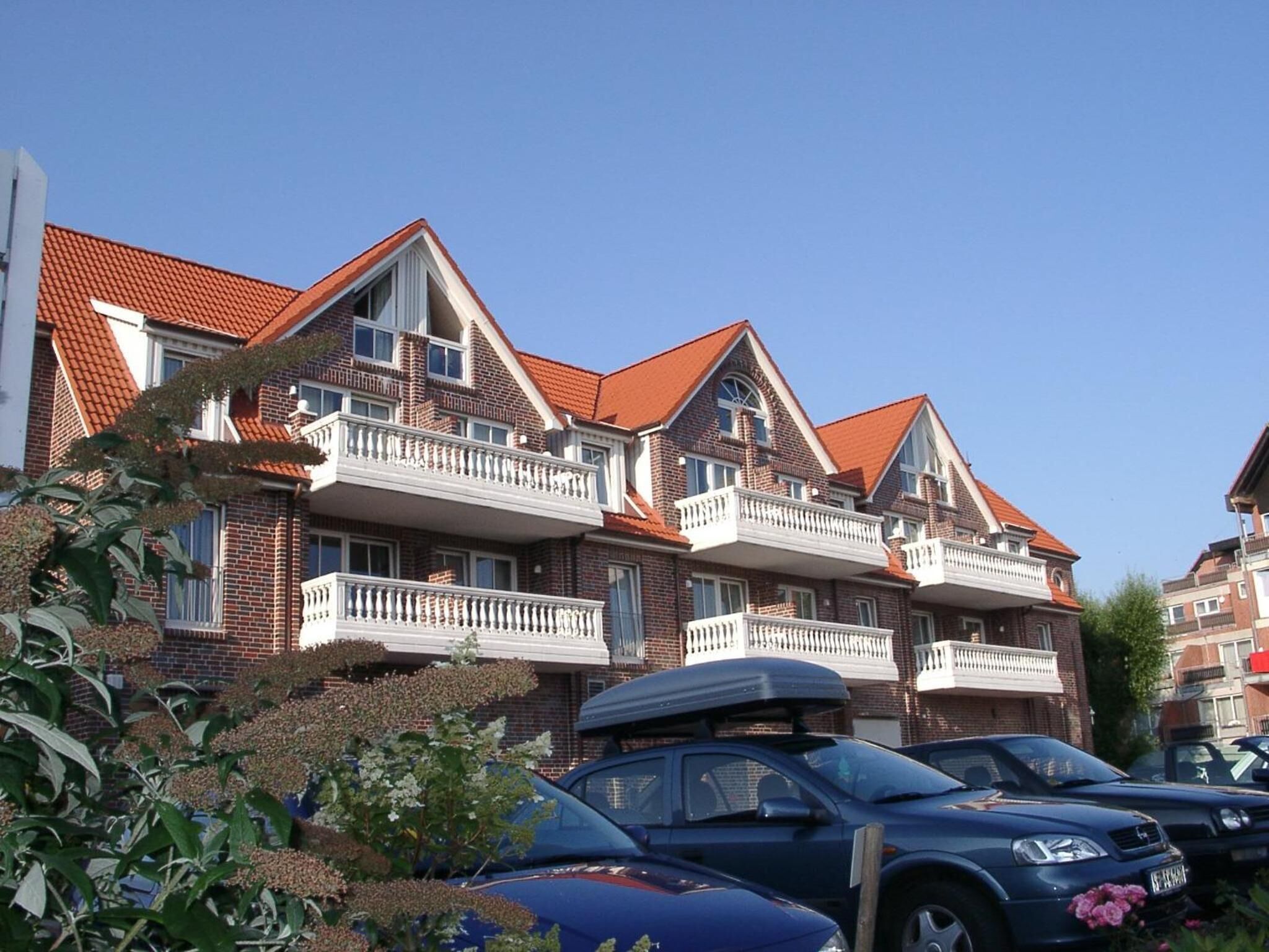 A multi-story residential building with brick facades, red-tiled roofs, and balconies.