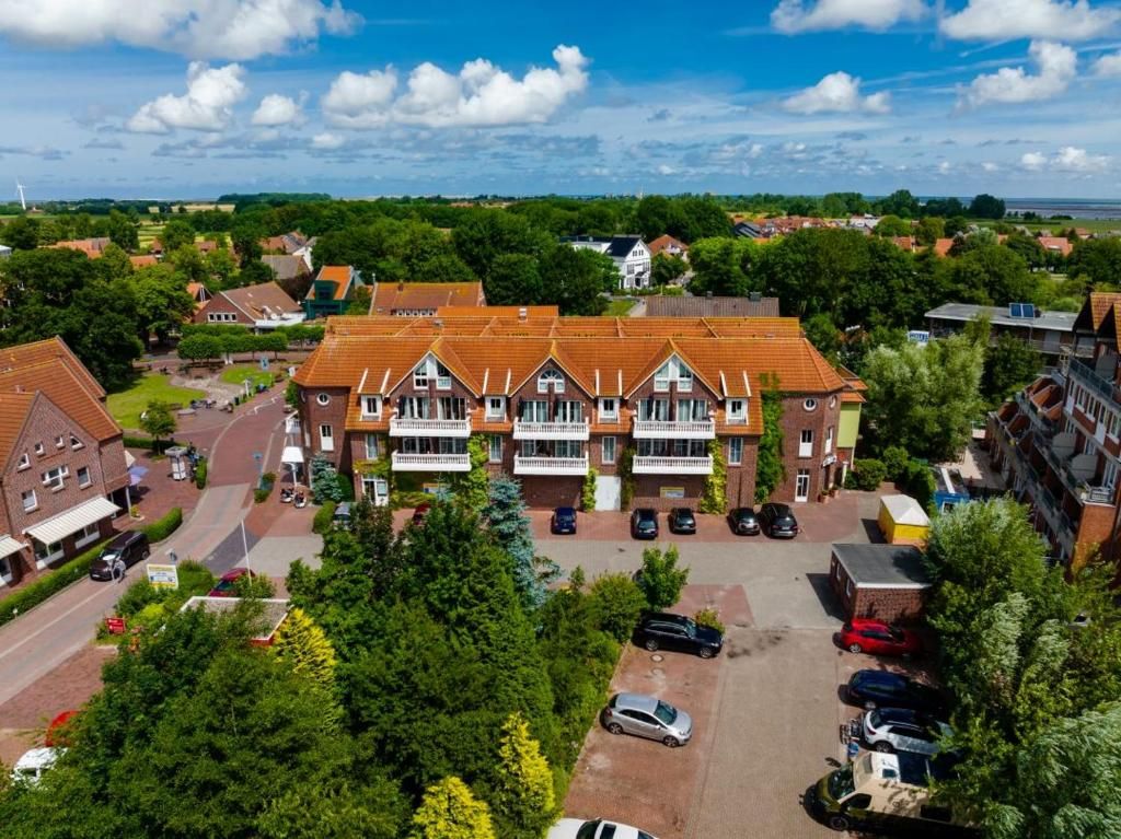 Ein mehrgeschossiges Wohngebäude mit einem zentralen Innenhof, umgeben von Grünflächen und parkenden Autos.