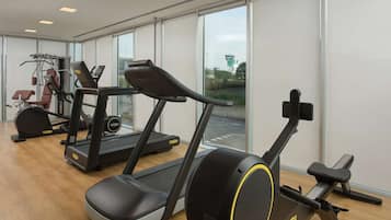 Une salle de sport équipée de tapis de course, d’un vélo d’appartement et d’un appareil d’aviron.