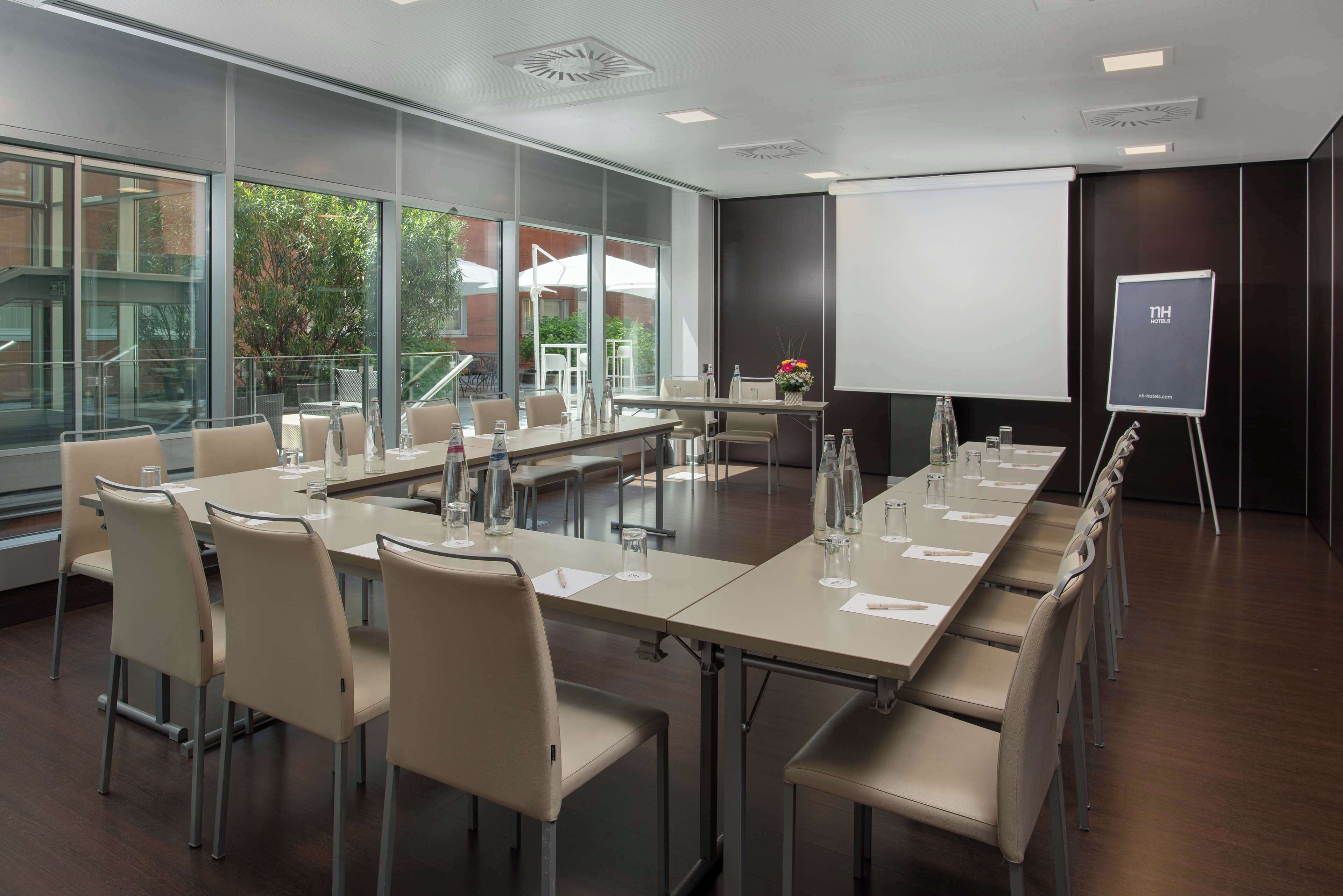 A conference room with a long table, chairs, a projector screen, and a whiteboard.