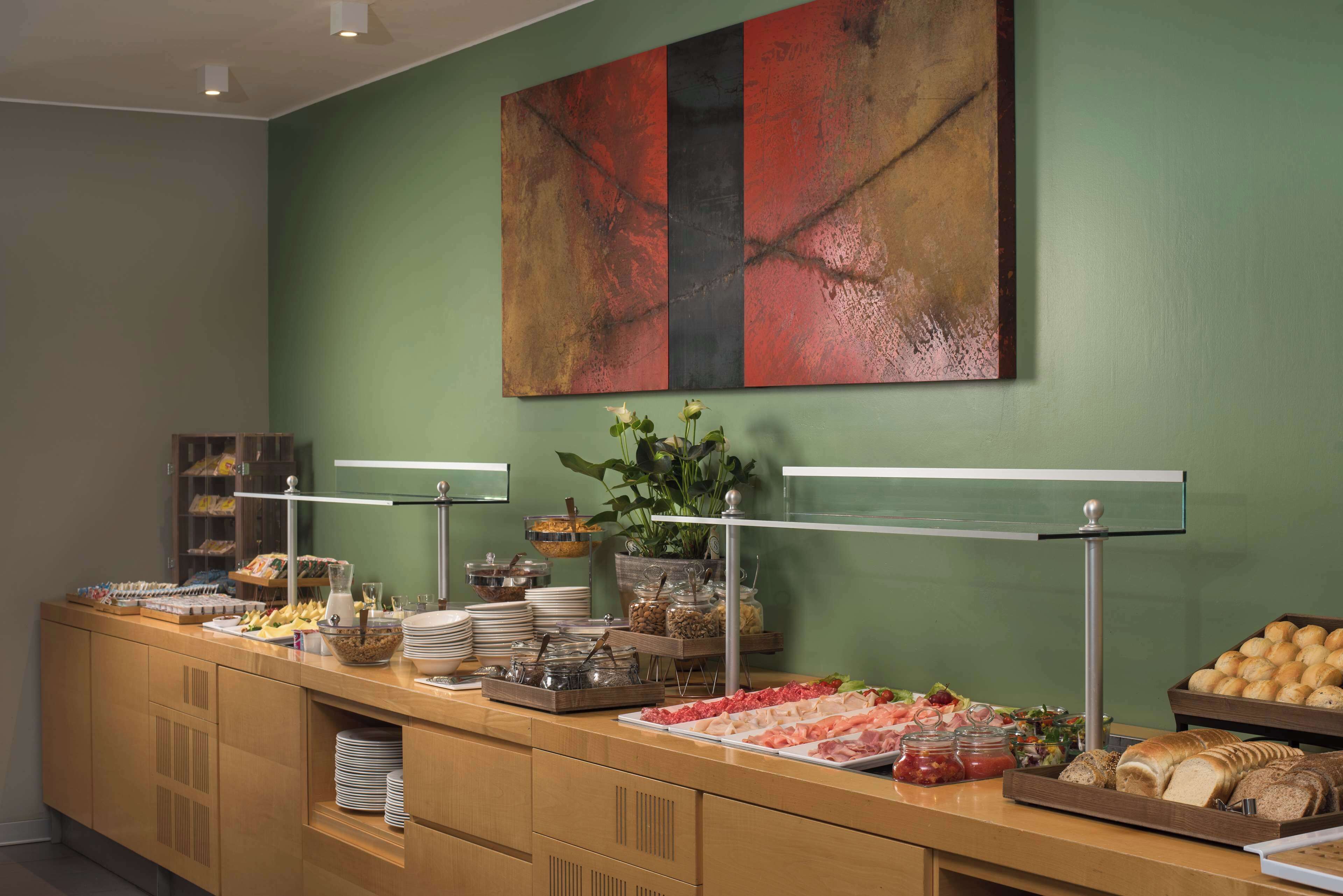 Un buffet garni de divers plats, un grand tableau abstrait accroché au mur et une plante en pot.