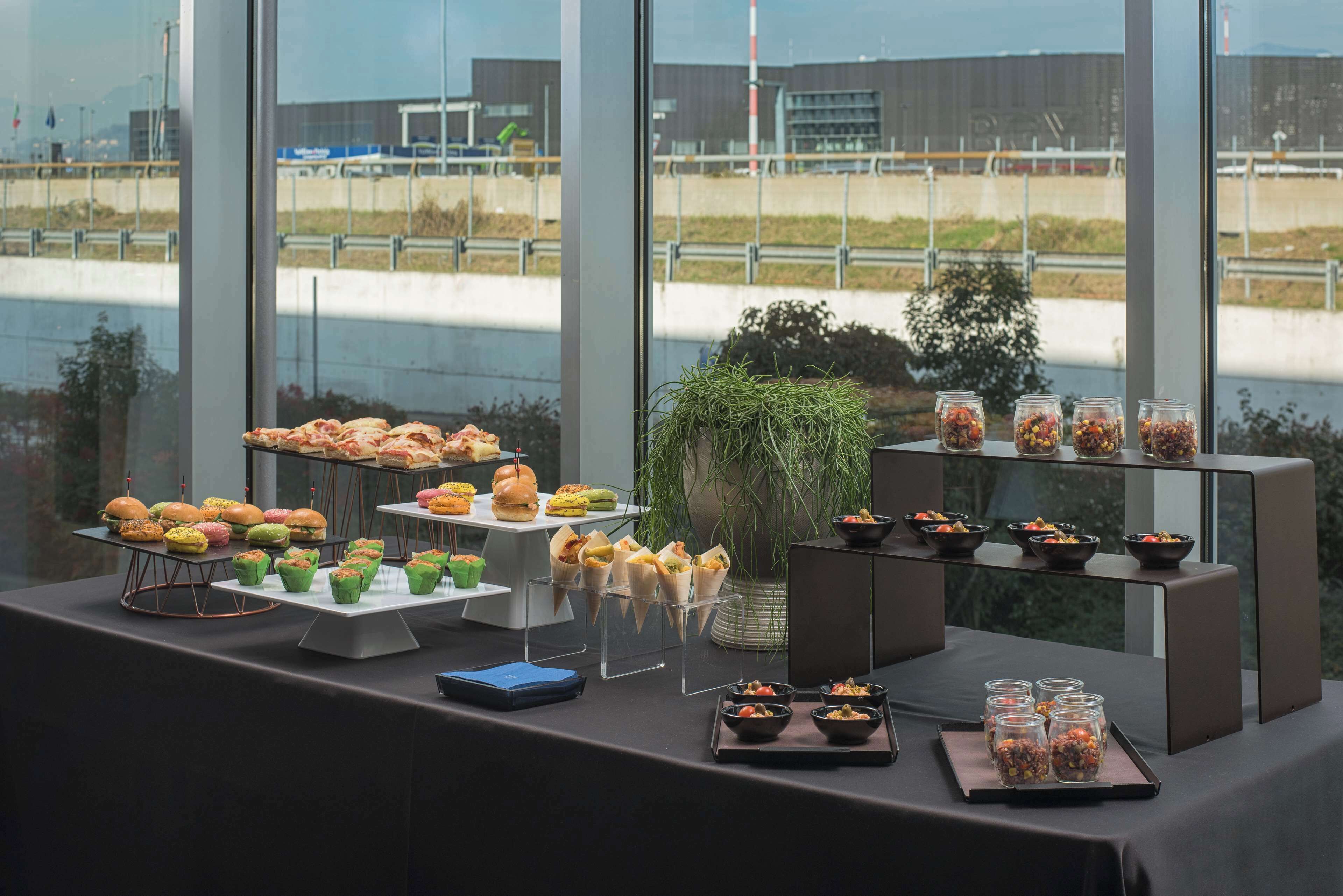 Uma mesa de buffet com diversos alimentos e um vaso de planta.
