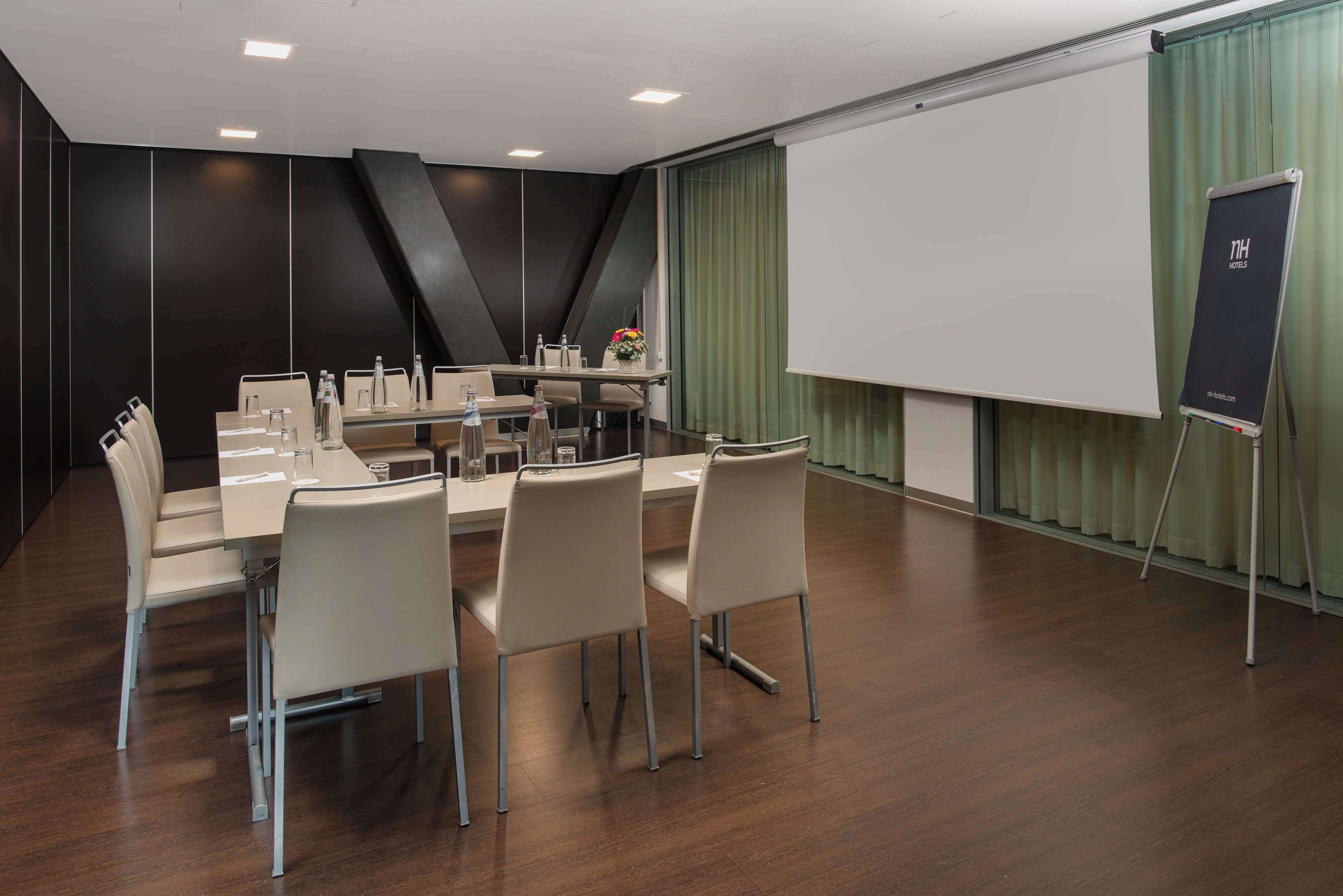 A conference room with a long table, chairs, a projector screen, and a flip chart.