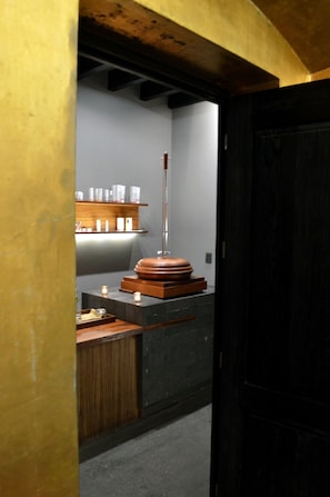 A room with a wooden bench, a shelf with toiletries, and a tall object in the center.