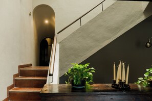 A staircase with a wooden handrail and a potted plant on the landing. - Dos Casas Hotel & Spa (San Miguel de Allende)