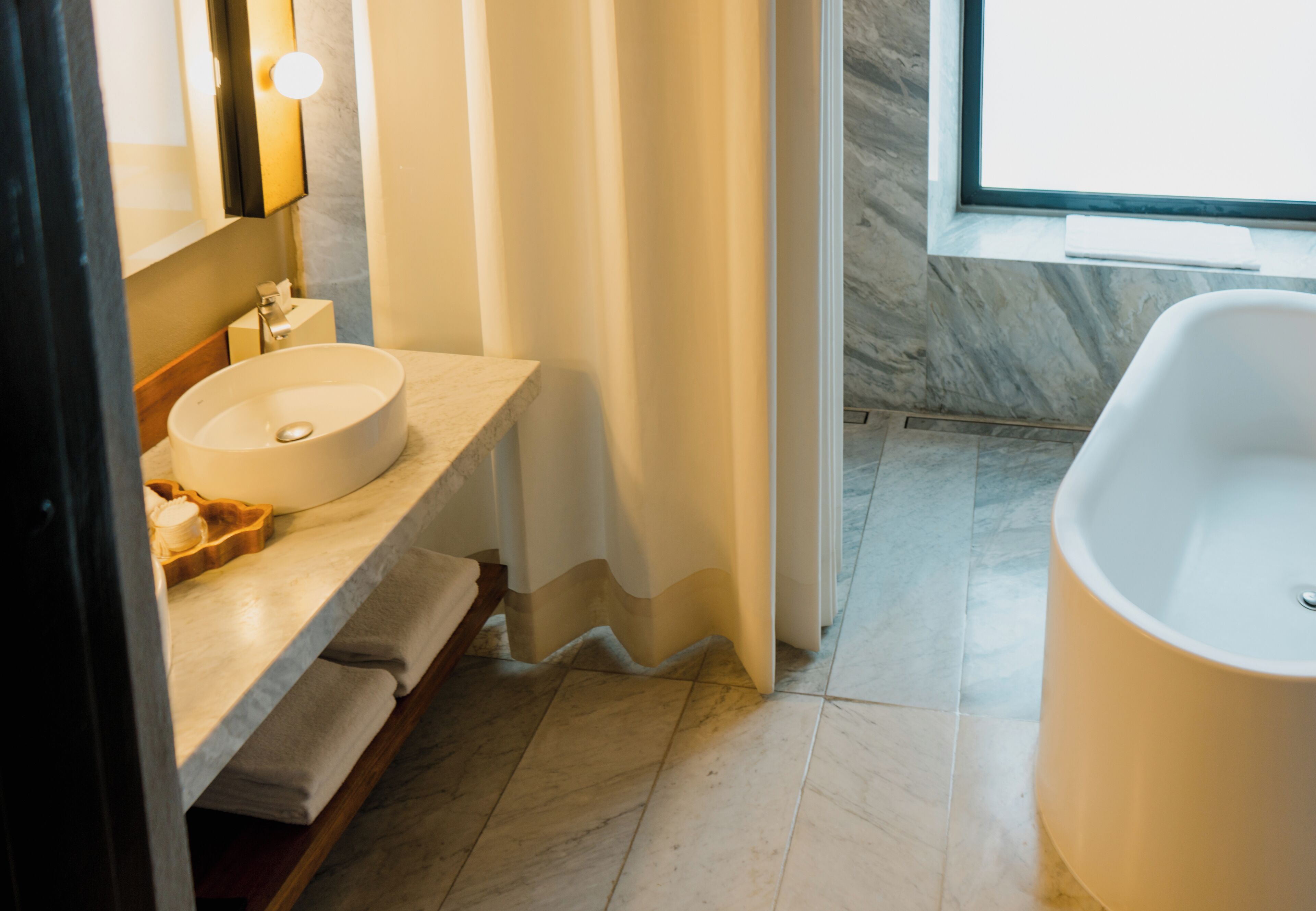 Un baño moderno con un lavabo redondo, una bañera y una zona de ducha.