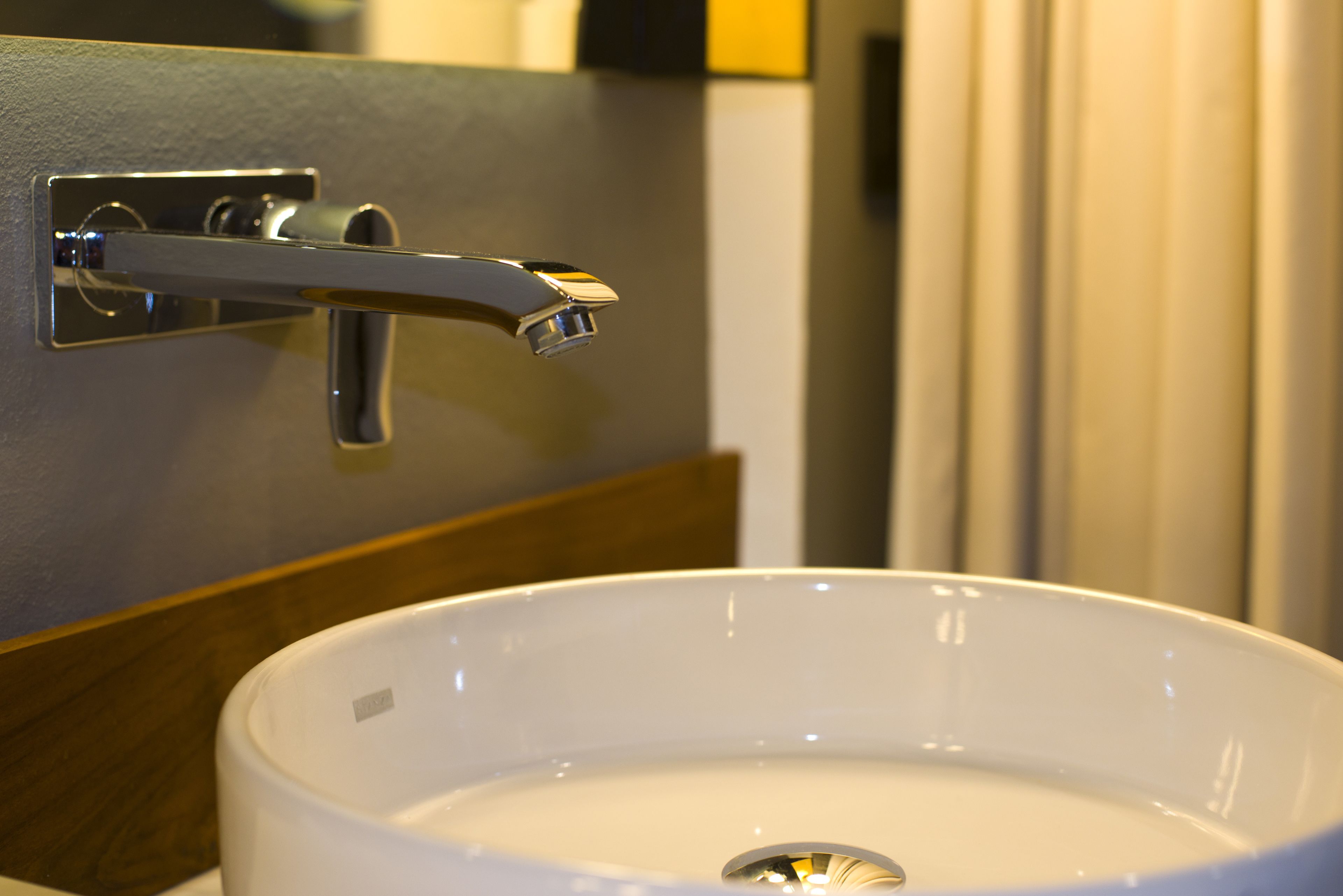 A bathroom with a white sink, a chrome faucet, and a wooden panel.
