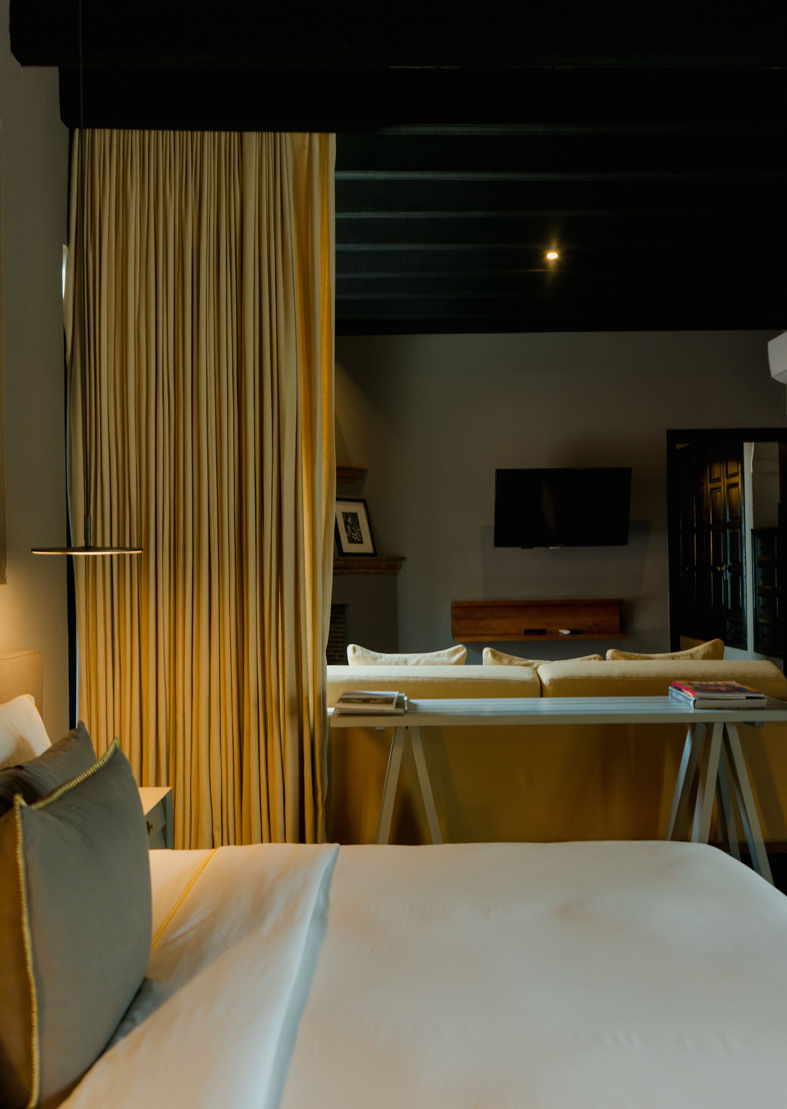 A hotel room with a bed, a desk, a chair, a television, and a curtain.