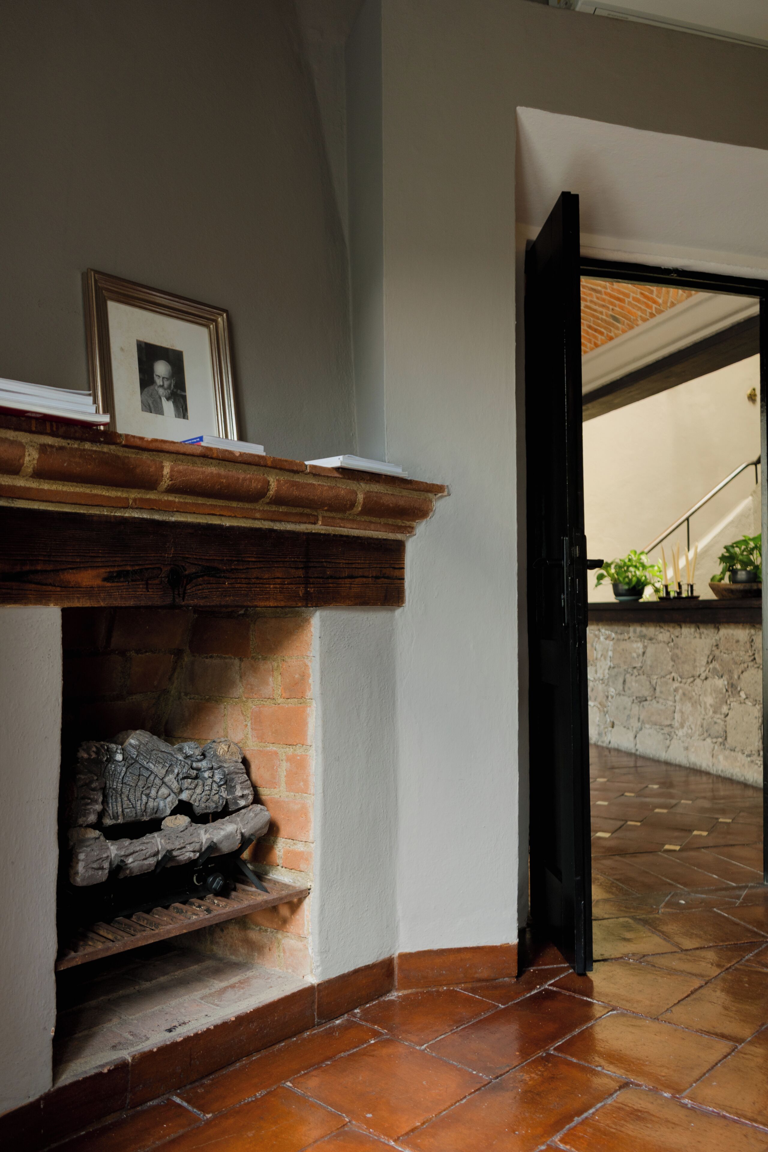 A fireplace with a mantel, a framed picture, and a brick wall.