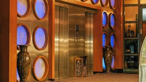 A lobby with a modern design, featuring a large elevator, a reception desk, and a patterned floor. - Peninsula Grand Hotel (Mumbai)
