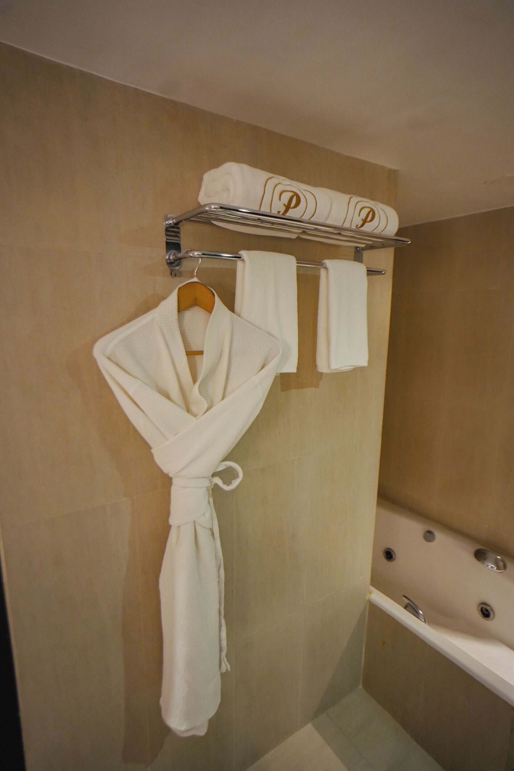 Une salle de bain avec une baignoire, un porte-serviettes avec deux serviettes et un peignoir accroché au mur.