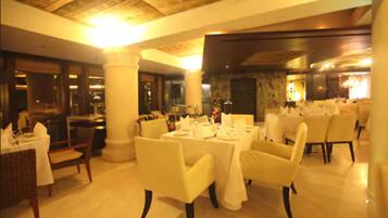 A restaurant with tables set for dining, white chairs, and a warm, well-lit interior.