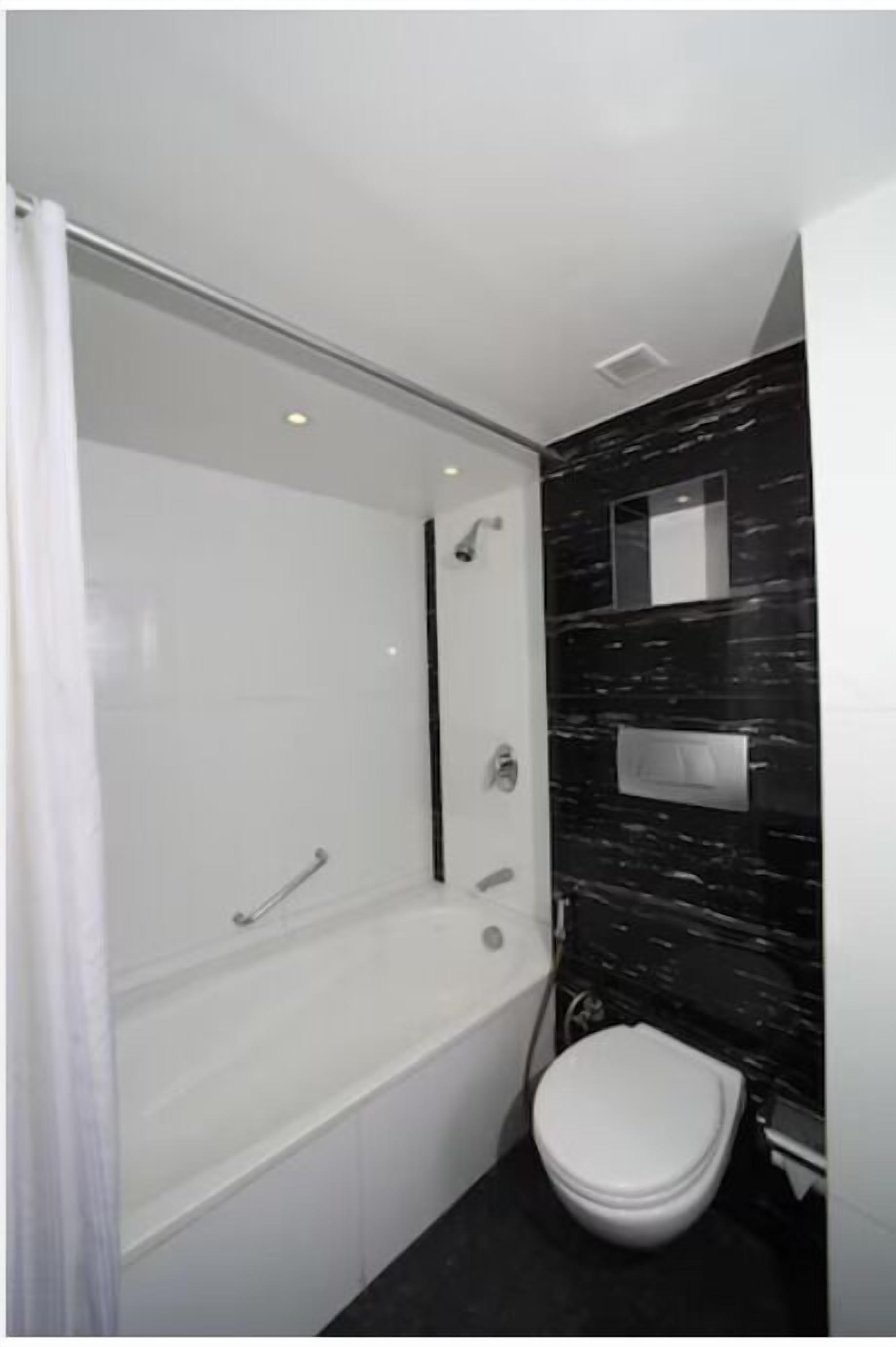 Ein modernes Badezimmer mit Badewanne, Toilette und Duschbereich.