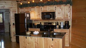A wooden cabin-style kitchen with a central island, stainless steel appliances, and a wooden floor.