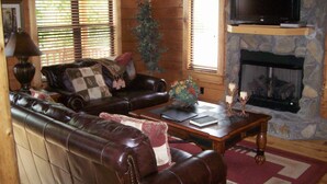 A cozy living room with a leather sofa, a coffee table, and a fireplace.