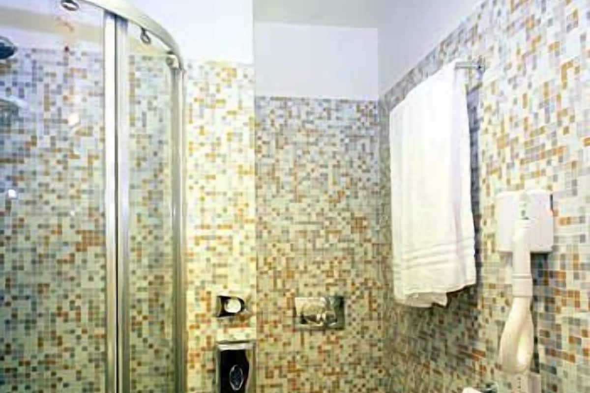 Un baño con cabina de ducha de vidrio, inodoro y lavamanos.