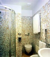 Un baño con cabina de ducha de vidrio, inodoro y lavamanos.