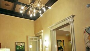 A hotel lobby with a wooden reception desk, a chandelier, a large mirror, and a painting on the wall. - Hotel Agathae (Catania)