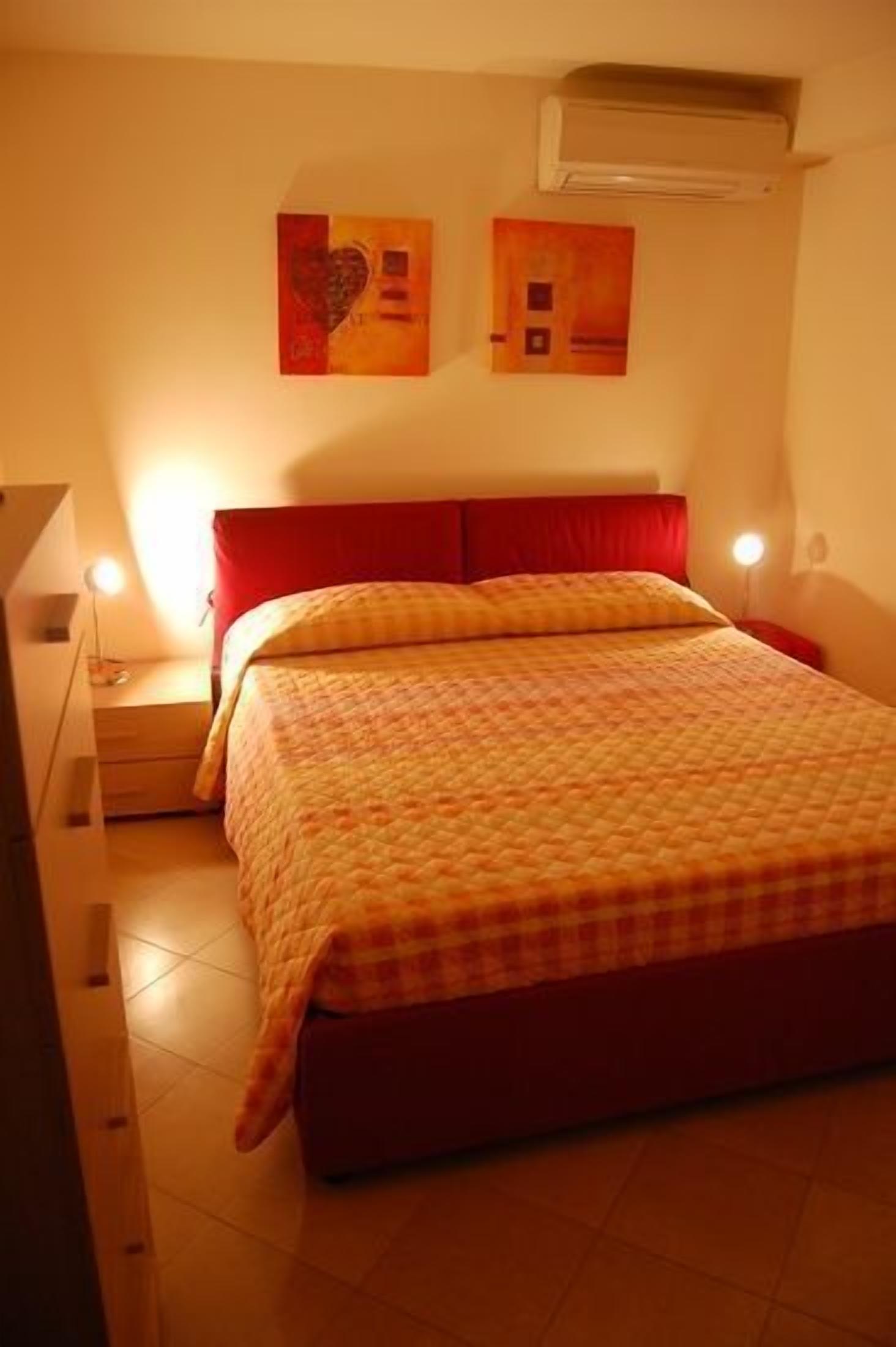 A bedroom with a bed, a nightstand, a lamp, and two wall art pieces.