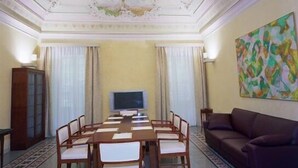 A conference room with a long table, chairs, a television, and a couch. - Hotel Agathae (Catania)