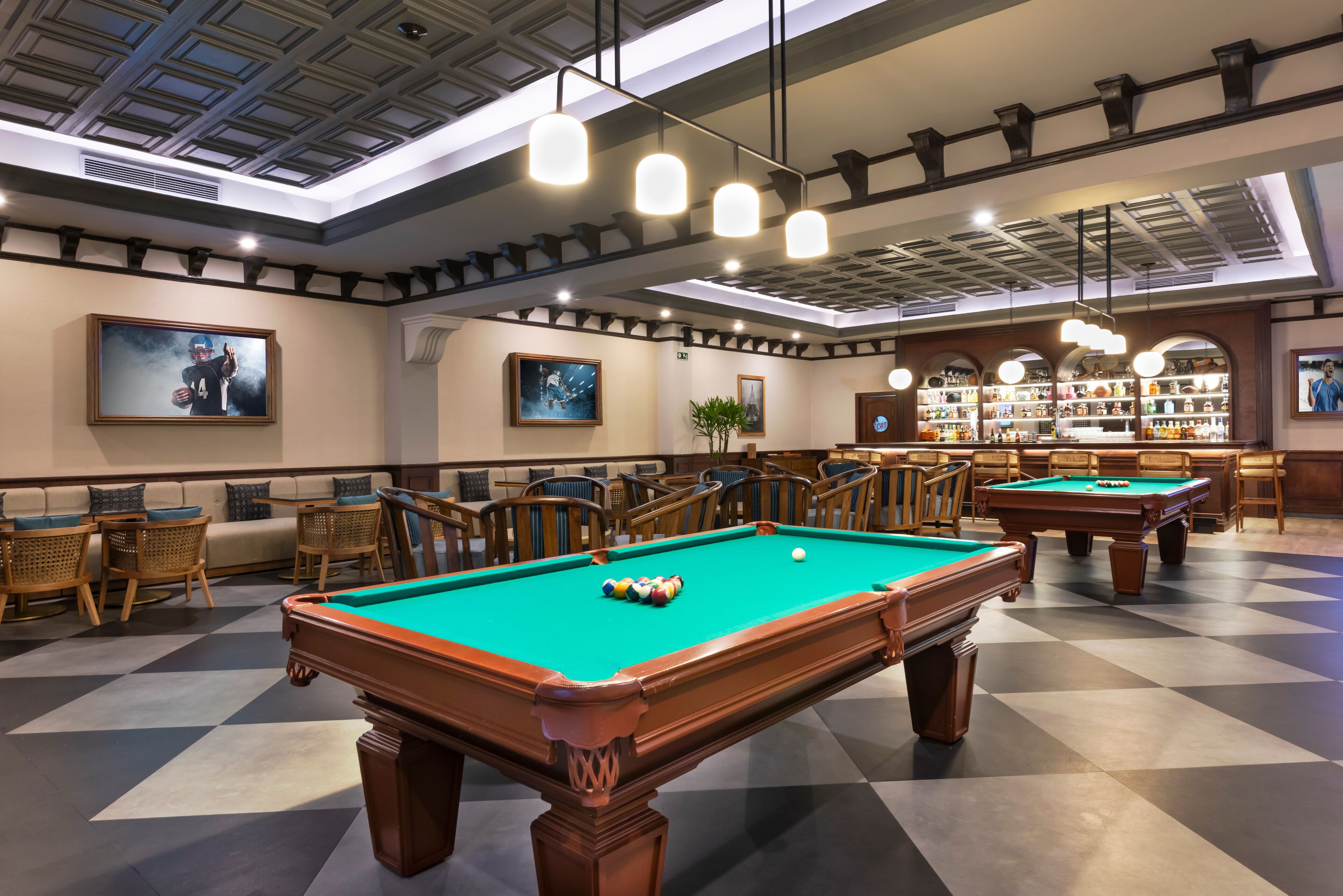 A pool table with a green felt surface, surrounded by wooden chairs and a sofa.