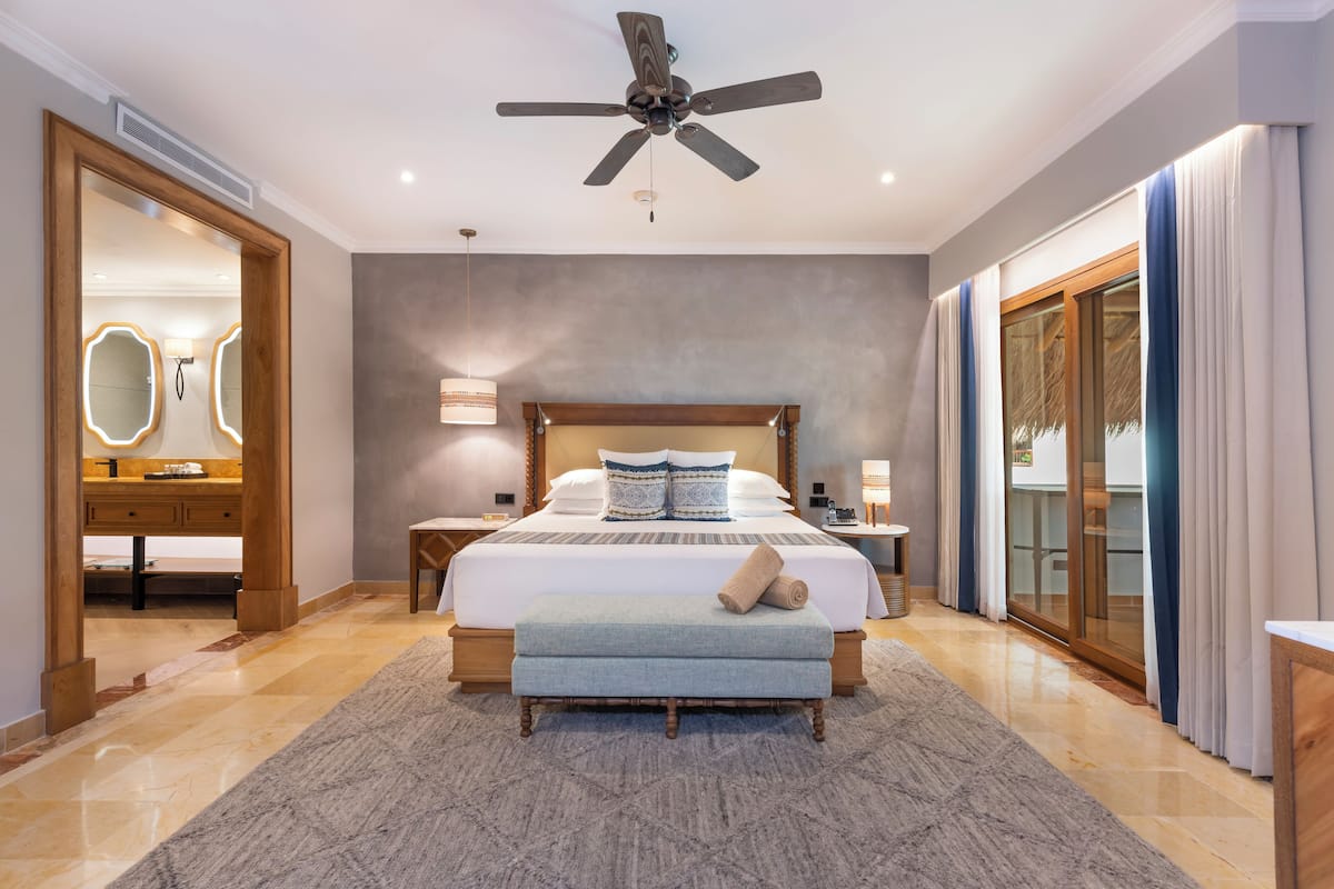 A modern bedroom with a large bed, a ceiling fan, a wooden headboard, and a large mirror.