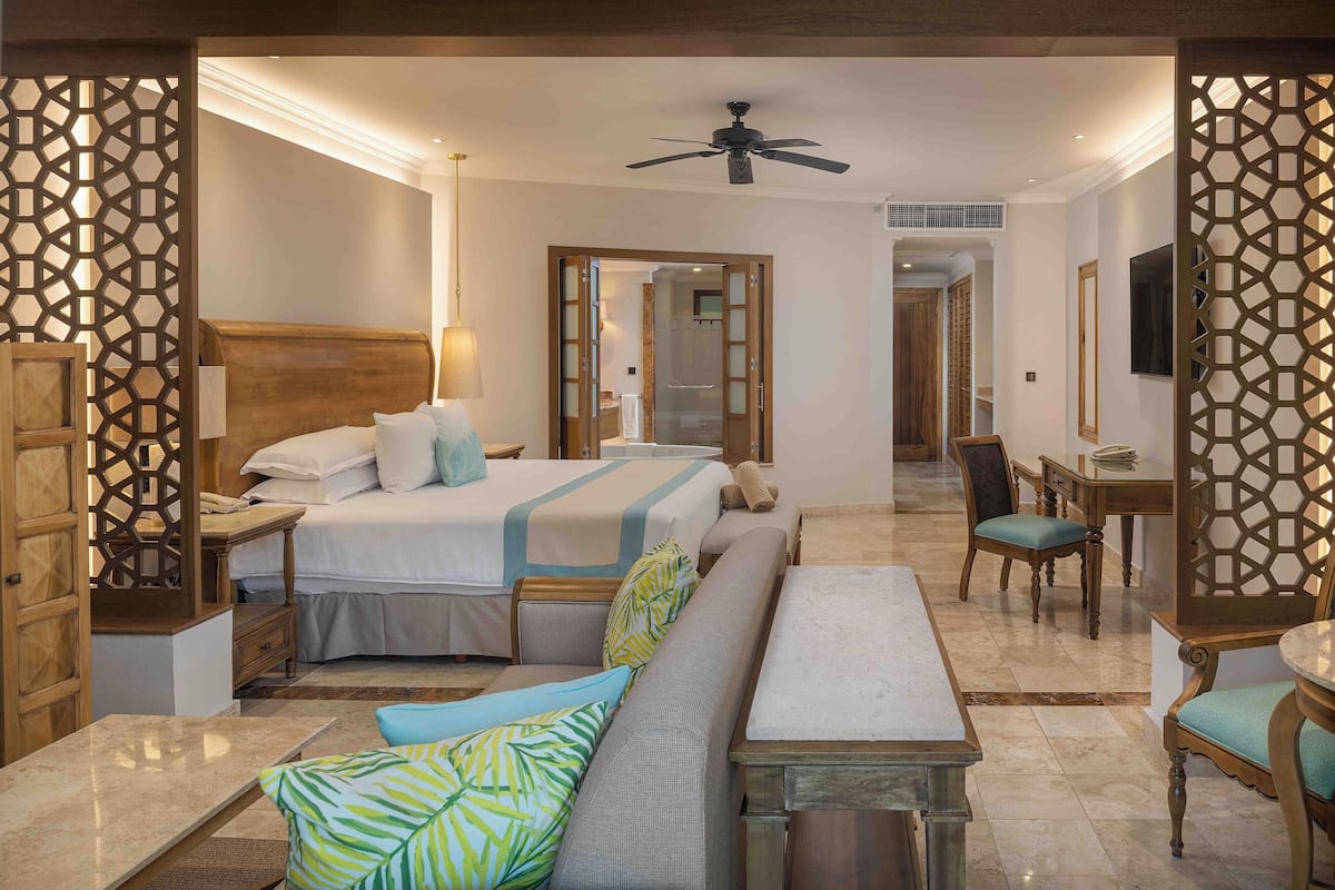 A hotel room with a bed, a sofa, a desk, and a chair.