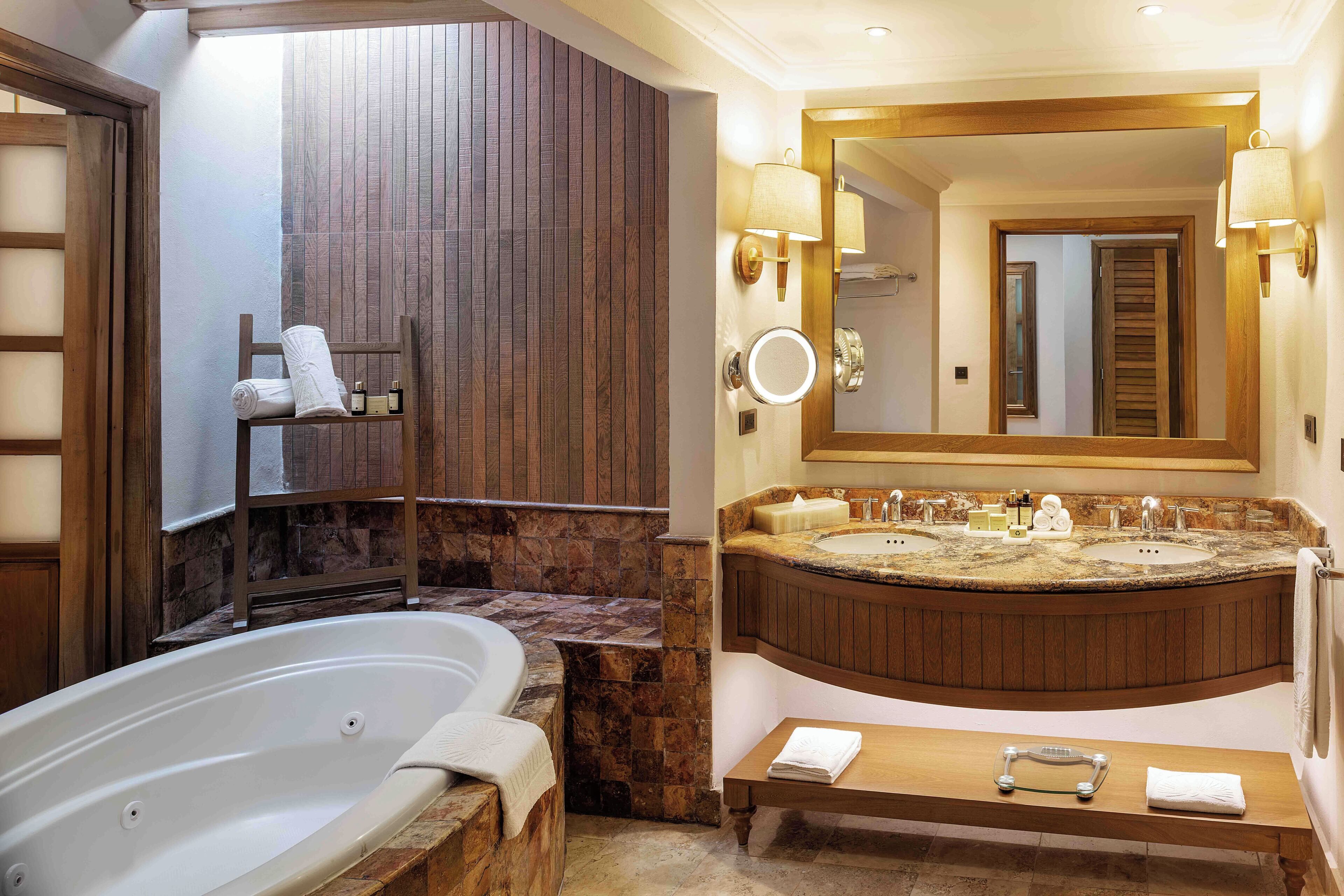 A modern bathroom with a freestanding bathtub, a large vanity with a double sink, and a mirror with wall sconces.