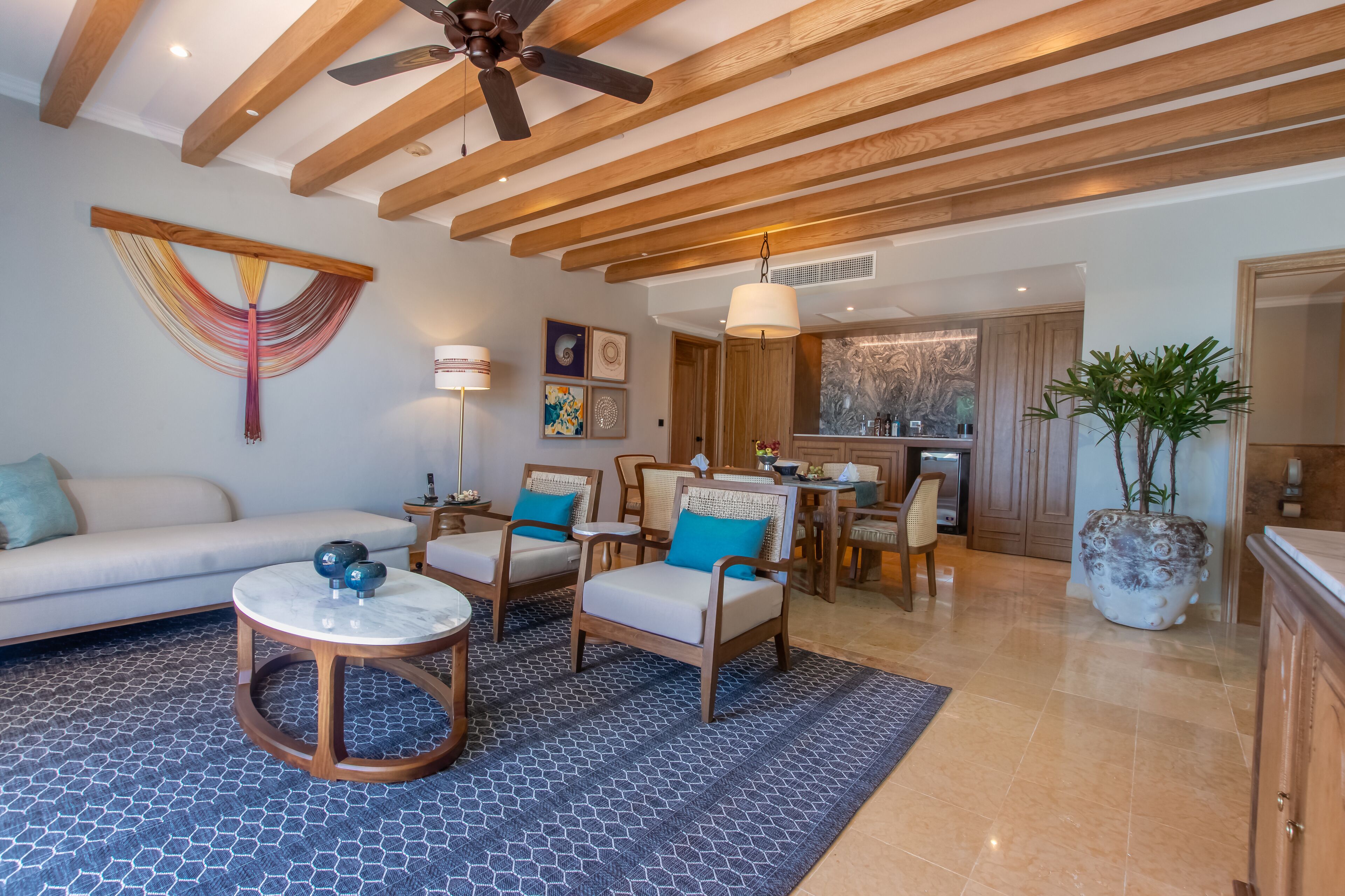 Amplia sala de estar con un sofá, dos sillones, una mesa de centro y un comedor con candelabro.