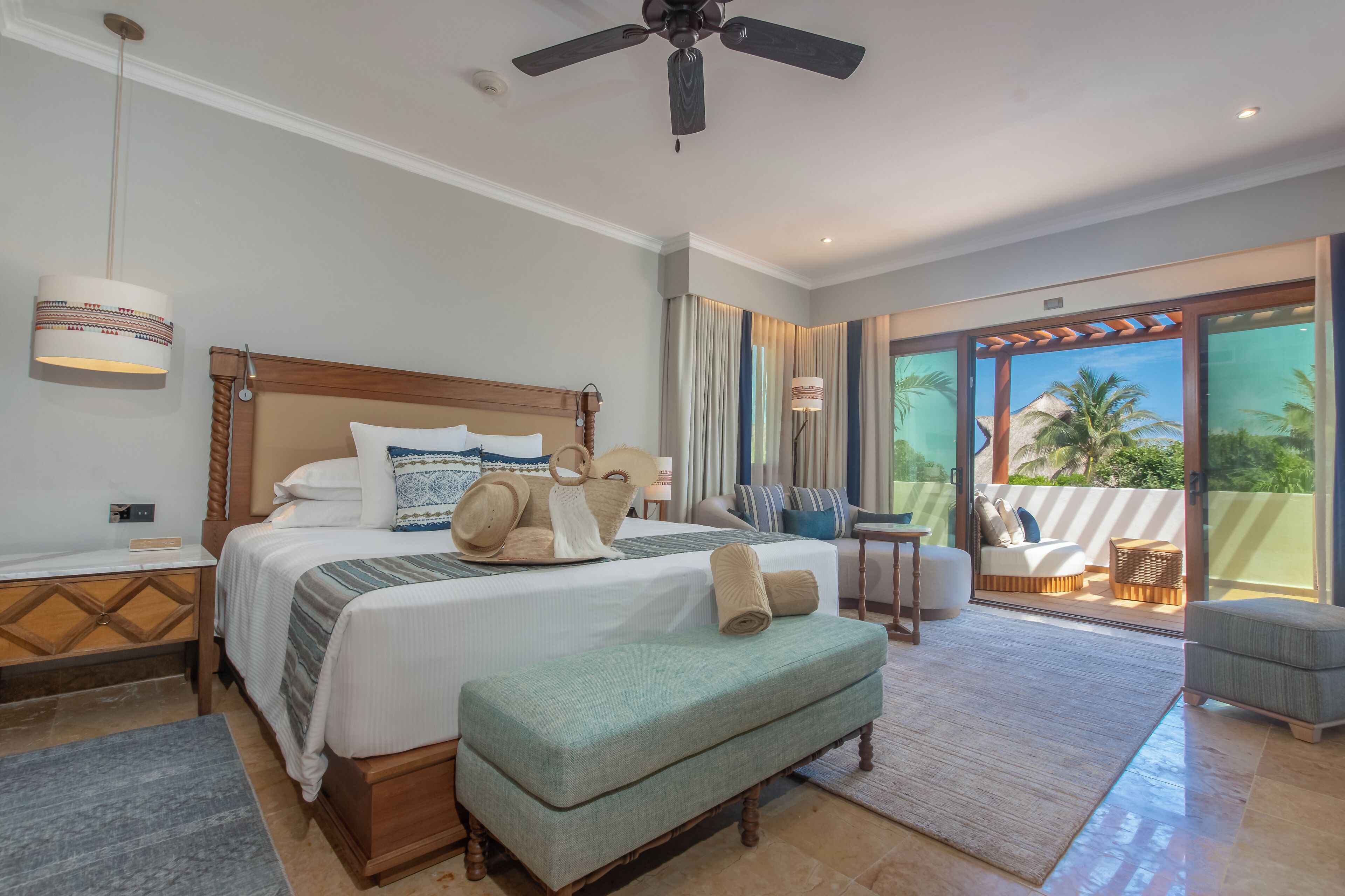 A spacious bedroom with a large bed, a ceiling fan, and a view of the outdoors.