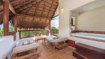 Un área de estar al aire libre con techo de paja, un jacuzzi y vistas de la vegetación circundante.