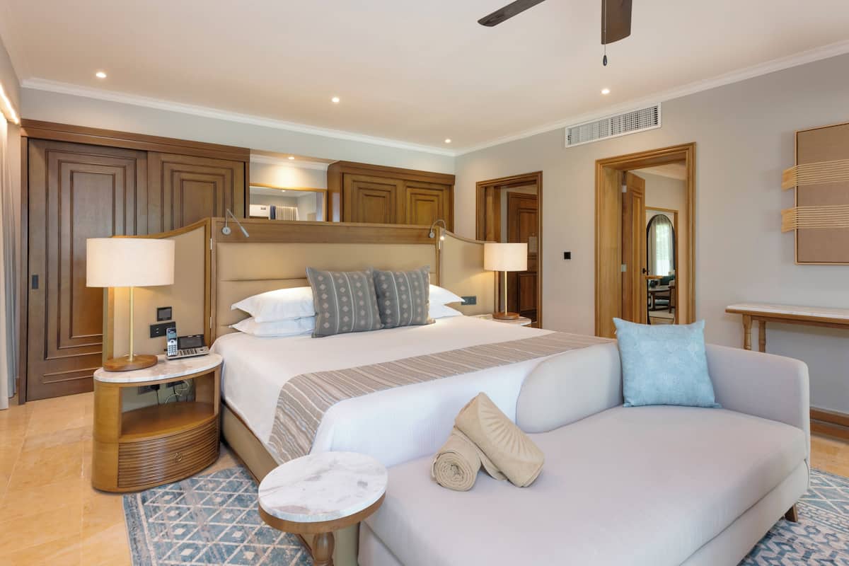A hotel room with a large bed, two bedside tables, a sofa, and a small round table.