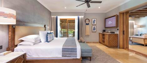 Un dormitorio amplio con una cama grande, un ventilador de techo, televisión y vistas al exterior.