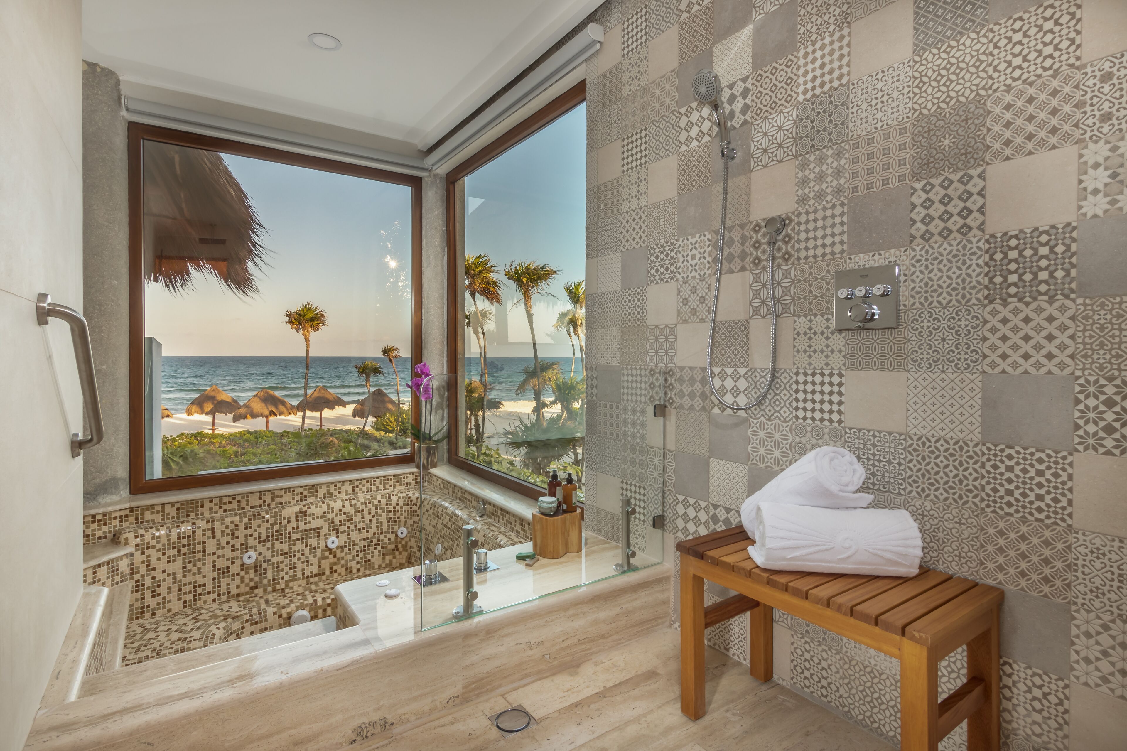 A bathroom with a large window, a shower, and a wooden bench.