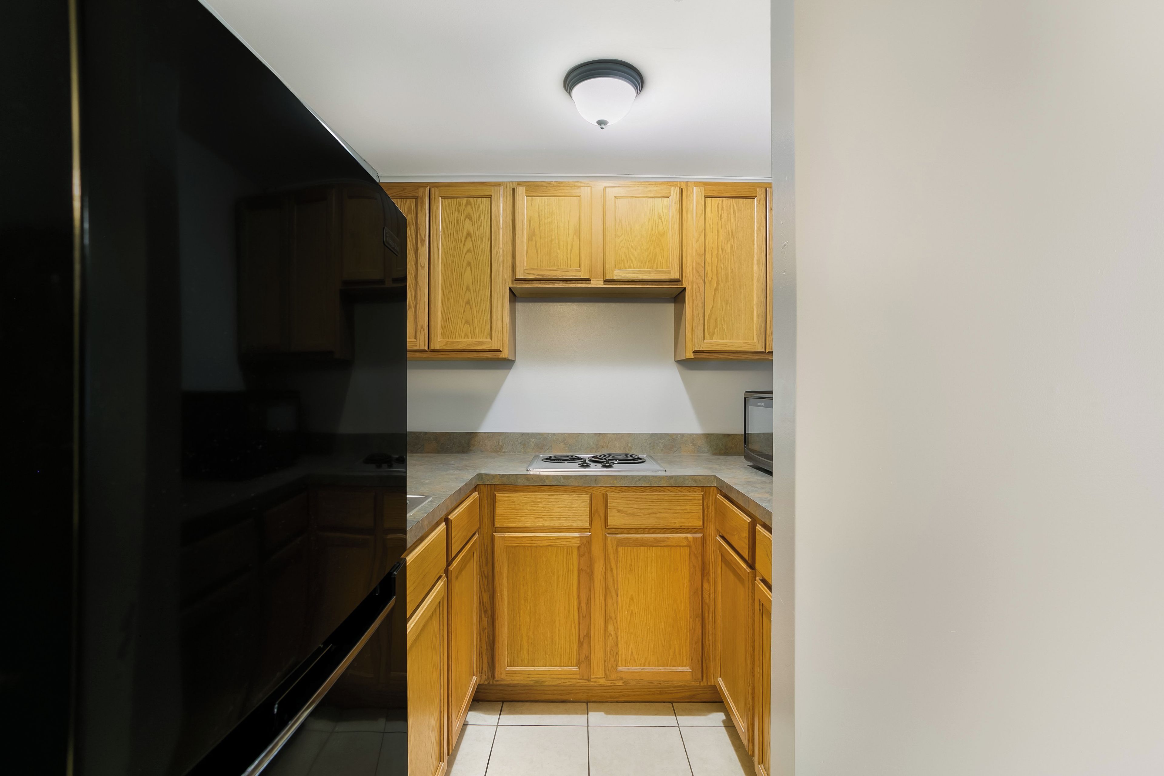 A kitchen with wooden cabinets, a stainless steel refrigerator, and a built-in microwave.